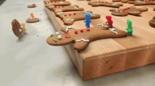 A Gingerbread Man Is Laying On A Wooden Cutting Board With Other Cookies GIF