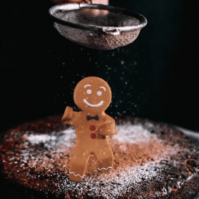 A Gingerbread Man With A Bow Tie Is Being Sprinkled With Powdered Sugar GIF