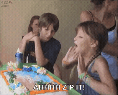 A Girl Blowing Out Candles On A Birthday Cake With The Words " Ahhhh Zip It " Written Below Her GIF