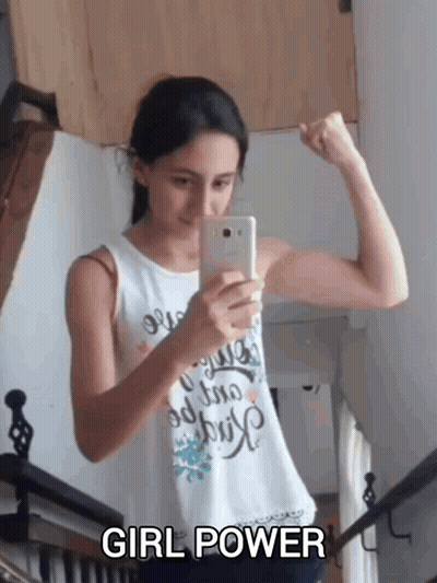 A Girl Flexes Her Muscles While Taking A Picture Of Herself With The Words Girl Power Below Her GIF