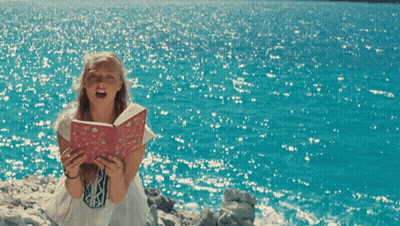 A Girl Holding A Book That Says ' I Love You ' On It GIF