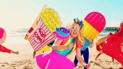 A Girl Holding A Popcorn Bucket On A Beach GIF