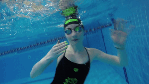 A Girl In A Black And Green Swimsuit Is Underwater GIF
