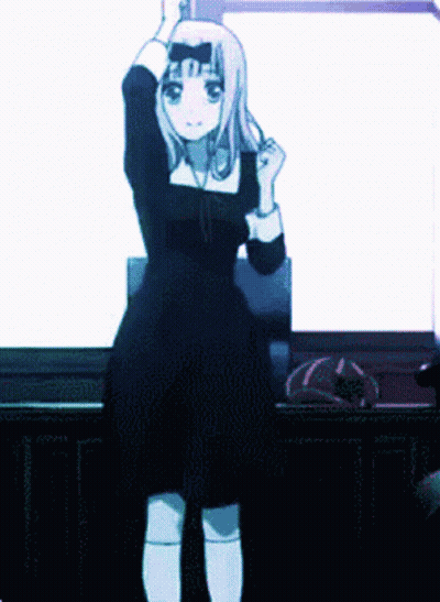 A Girl In A Black Dress Is Standing In Front Of A White Wall . GIF