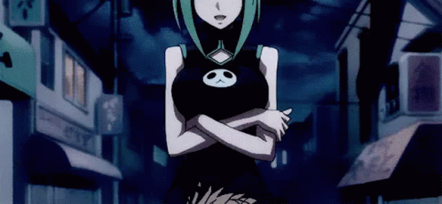 A Girl In A Black Dress With A Skull On Her Chest Is Standing In A Dark Street . GIF