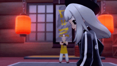 A Girl In A Black Jacket With The Letter G On The Back Stands In Front Of A Man In A Yellow Shirt GIF