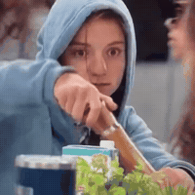 A Girl In A Blue Hoodie Is Holding A Knife . GIF