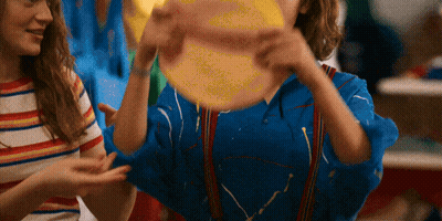 A Girl In A Blue Shirt Is Holding A Yellow Ball GIF
