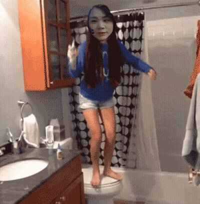 A Girl In A Blue Shirt With The Letter O On It Is Standing On A Toilet GIF