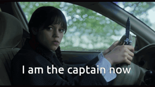A Girl In A Car Holding A Knife With The Words " I Am The Captain Now " Above Her GIF