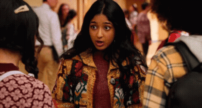 A Girl In A Colorful Jacket Is Talking To Another Girl In A Plaid Shirt GIF