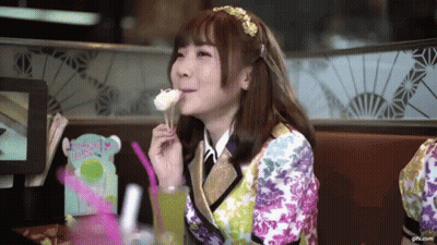 A Girl In A Colorful Outfit Is Eating A Piece Of Cake GIF