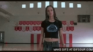 A Girl In A Crop Top Is Standing In A Gym . GIF