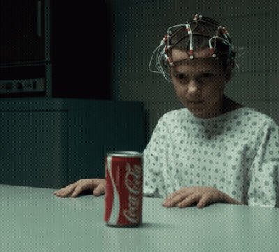 A Girl In A Hospital Gown Sits At A Table With A Can Of Coca Cola On It GIF