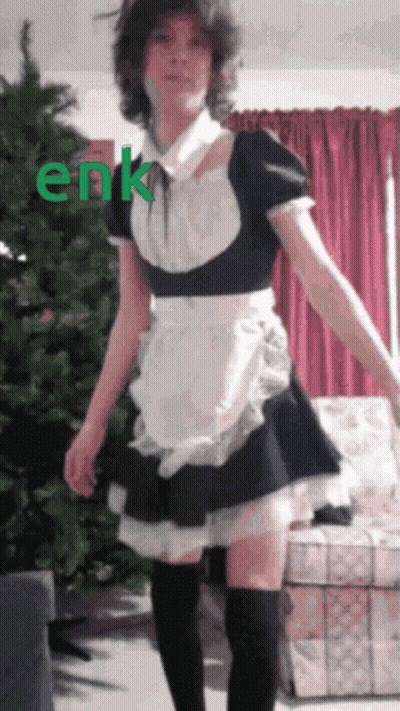 A Girl In A Maid Costume Is Standing In Front Of A Christmas Tree With The Word Enk Written In Green GIF
