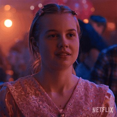A Girl In A Pink Dress Is Sitting In A Room With A Netflix Logo On The Bottom Right Corner . GIF