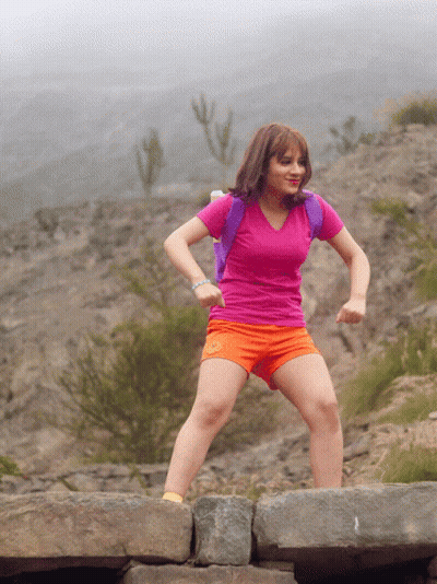 A Girl In A Pink Shirt And Orange Shorts Is Jumping On A Rock GIF