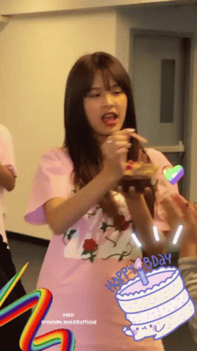A Girl In A Pink Shirt Is Holding A Birthday Cake With A Candle On It GIF