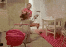 A Girl In A Pink Shirt Is Playing With A Toy Stroller GIF