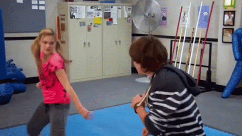 A Girl In A Pink Shirt Is Standing Next To A Boy In A Black And White Striped Shirt GIF