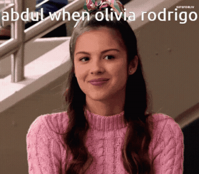 A Girl In A Pink Sweater Is Smiling With The Caption Abdul When Olivia Rodrigo Above Her GIF