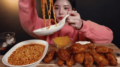 A Girl In A Pink Sweatshirt Is Eating Noodles And Chicken GIF