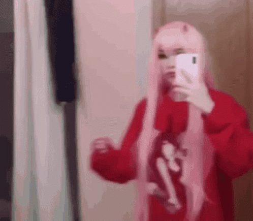 A Girl In A Pink Wig Is Taking A Selfie With Her Phone . GIF