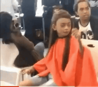 A Girl In A Red Cape Is Sitting At A Table In A Room . GIF