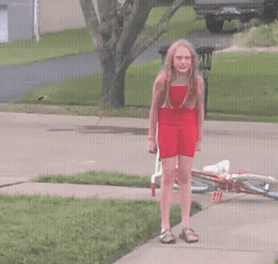 A Girl In A Red Dress Is Walking Past A Trash Can That Says Yard On It GIF