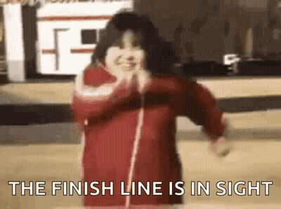 A Girl In A Red Jacket Is Dancing In Front Of A Building And The Finish Line Is In Sight . GIF