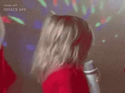A Girl In A Red Sweater Is Holding A Microphone And Singing . GIF