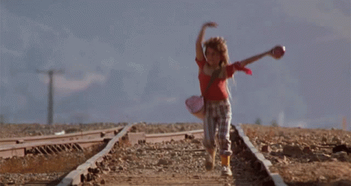 A Girl In A Red Top Is Running On Train Tracks GIF