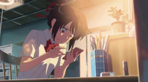 A Girl In A School Uniform Is Looking At Her Cell Phone GIF