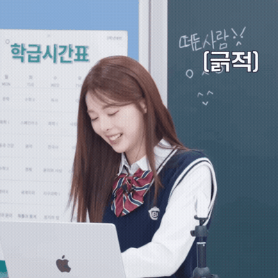 A Girl In A School Uniform Is Smiling While Looking At An Apple Laptop GIF