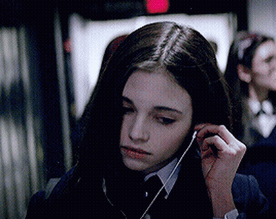 A Girl In A Suit And Tie Is Listening To Music GIF