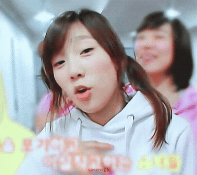A Girl In A White Hoodie Is Making A Funny Face In Front Of Another Girl GIF
