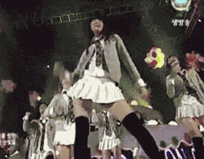 A Girl In A White Skirt And Black Knee High Socks Is Dancing On Stage GIF
