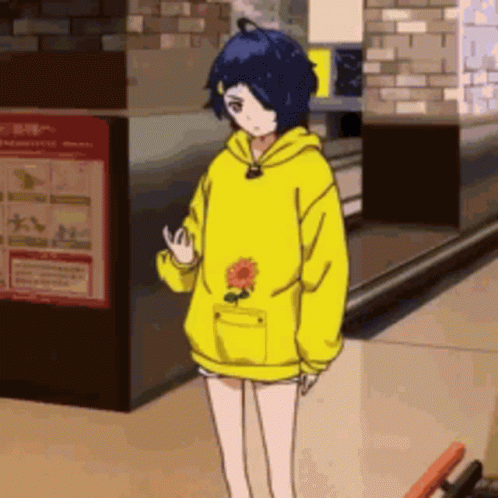 A Girl In A Yellow Hoodie With A Flower In Her Pocket Is Standing In A Hallway . GIF