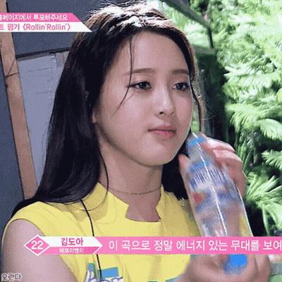 A Girl In A Yellow Shirt Is Holding A Water Bottle GIF