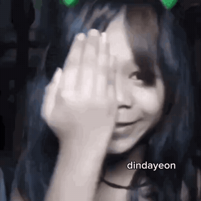 A Girl Is Covering Her Face With Her Hand And Smiling . GIF