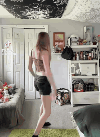 A Girl Is Dancing In A Bedroom With A Bag That Says ' O'neill ' On It GIF