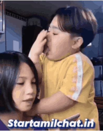A Girl Is Holding A Child Who Is Covering His Nose With His Hand GIF