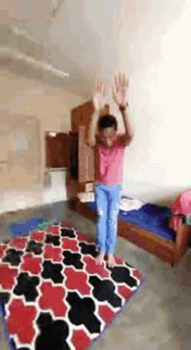 A Girl Is Jumping In The Air In A Room With A Rug . GIF