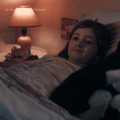 A Girl Is Laying In Bed With A Lamp And The Words La Guardia Festival On The Bottom Right GIF