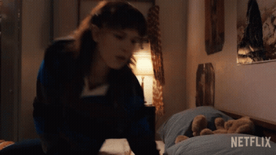 A Girl Is Laying On A Bed With A Teddy Bear And A Netflix Logo In The Corner . GIF