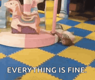 A Girl Is Laying On The Floor In Front Of A Merry Go Round And Says Everything Is Fine . GIF