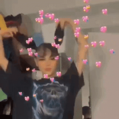 A Girl Is Making A Heart Shape With Her Hands In Front Of A Mirror . GIF