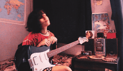 A Girl Is Playing A Guitar In Front Of A Clock That Says 8:51 GIF