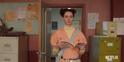 A Girl Is Reading A Book In A Room With A Netflix Logo GIF