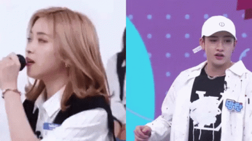 A Girl Is Singing Into A Microphone And A Man Is Standing Next To Her . GIF